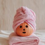 Prompt:Orange pumpkin with pink towel wrapped on...