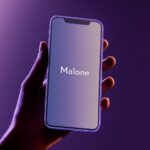 A hand holding an iPhone with the design of its logo "Malone" displayed on it, a...