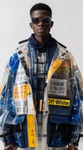 A man is wearing an oversized, transparent plastic jacket with blue and yellow J...
