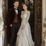 A stunning bride and groom in modern Regency-inspired wedding attire, standing t...
