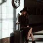 A woman in an elegant suit with black shoes and hat is sitting on top of her lar...