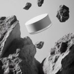 A white cosmetic jar floating in the air, surrounded by rocks, photographed from...