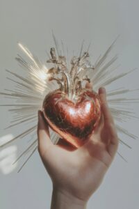 An antique hand holding the sacred heart of divine love, with silver ornaments a...
