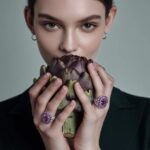A portrait of a young woman with refined features, holding a large artichoke in ...
