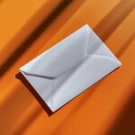 An image of a white blank envelope on top of an orange table --v 6.1by joseczrs#...