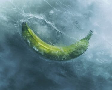 Overhead view of the blurred outline of a green banana frozen under the surface ...