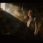 In the dim interior of an antique shop, a man in his mid-forties stands in a foc...