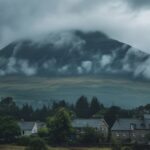 A large mountain in the background, surrounded by green trees and houses in the ...