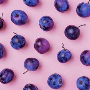 flat lay of purple plumbs on a pastel pink background,in the style of digital mi...