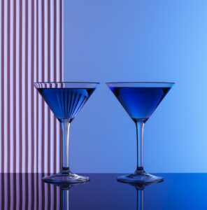 one of two cocktail glasses with a blue liquid in front of them, in the style of...