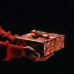side view of a person gripping a large bright green holiday gift over a black ba...