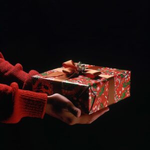 side view of a person gripping a large bright green holiday gift over a black ba...