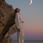 an editorial photo an androgynous male, moon, island, sunrise, celestial mystici...