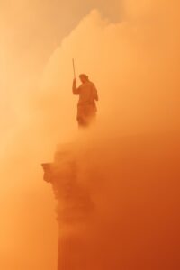 close up detail shot ,tiny greek Statue on a top of giant column, Orange Heat Ha...