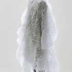 A model wearing a voluminous white peacock coat made of many white patterns on t...