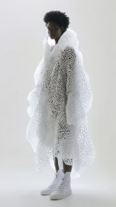A model wearing a voluminous white peacock coat made of many white patterns on t...