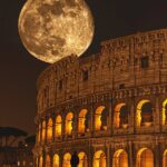 A solitary person standing in front of the illuminated Colosseum in Rome, with a...
