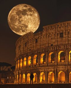 A solitary person standing in front of the illuminated Colosseum in Rome, with a...