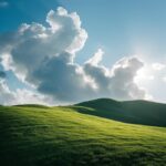 photography of large of clouds resting on a green hillside, basking in the brigh...