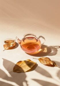 A glass teapot of wolfberry tea lies on oiled leaves and next to it is a small c...