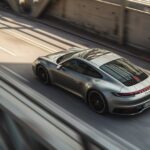 a commercial photo of a silver porsche 992 driving in a tunnel in an urban envir...