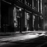 A solitary pedestrian traversing the black and white city streets, with building...
