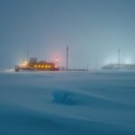 photograph of a distant research station based in antarctica studying snow depth...