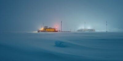 photograph of a distant research station based in antarctica studying snow depth...