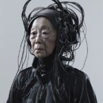 an old Asian woman in black with a futuretech sandblasted face shield on her hea...