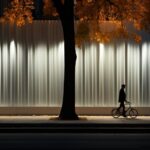 An individual riding a bike along a pedestrian path through a tall white streaml...