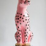 A ceramic lamp with a black base and gold metal accents, the body of a cheetah i...