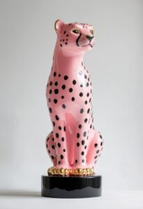 A ceramic lamp with a black base and gold metal accents, the body of a cheetah i...