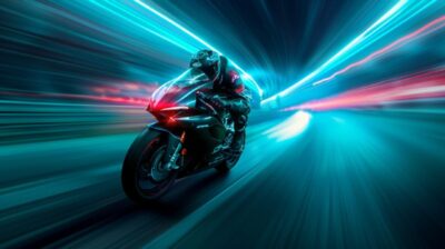 A MotoGP rider speeding down a neon-lit road, with trails of bright blue and gre...