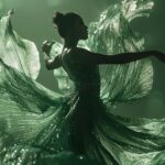 Movement of a woman dressed as a blooming Iris posing in the light, beautiful si...