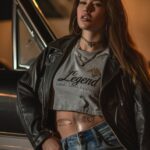 Photo of american woman wearing jeans and leather jacket, with long hair, she is...