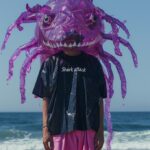 the close up portrait of person wearing an oversized lavender shirt and pink pan...