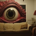We see a livingroom and outside of the window is a cute godzilla eye looking ins...