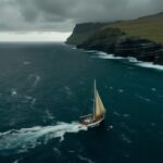 A drone shot of a sailboat near the Faroe islands. on choppy seas with rain clou...