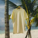 long oversized t-shirt in light yellow color, hanging on a hanger on a palm tree...