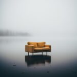 Photo of a brocken big sofa sticking out of the lake, fog mads berg, design chai...