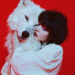 surealistic photography A girl with short black hair hugging the head of a white...